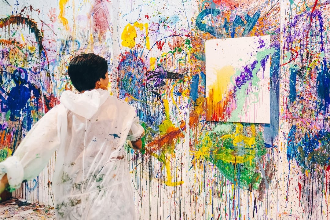 Boy throwing paint on the wall by Splat Paint House